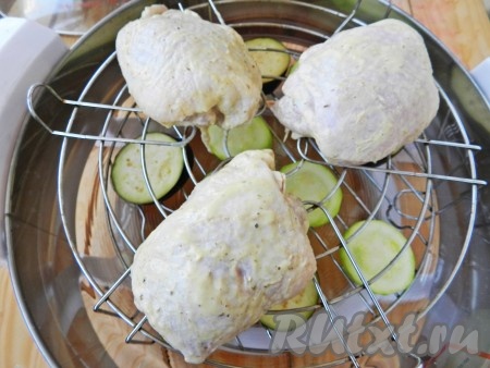 На нижней решетку аэрогриля разложить овощи. Установить верхнюю решетку и выложить на нее куриные бедра.