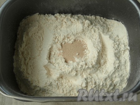 Добавить в ведёрко просеянную муку и сверху всыпать дрожжи.