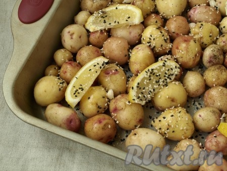 Молодой картофель вымыть и почистить щёточкой, чтобы убрать кожуру (тщательно очищать кожуру не нужно). Выложить картофель в форму для запекания в один слой. Посыпать смешанным кунжутом и выложить нарезанный дольками лимон.
