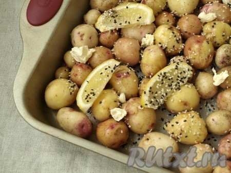 Сверху на картофель положить кусочки сливочного масла и разбросать произвольно нарезанный пластинками чеснок. Посолить и поперчить картофель.