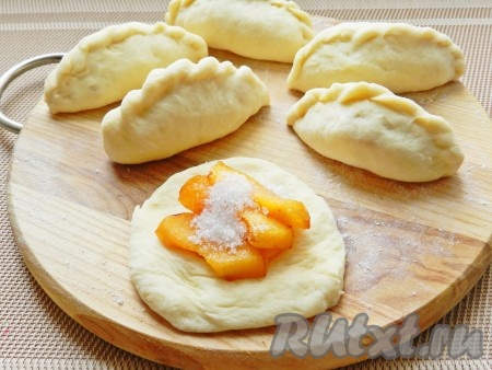 Кусочки теста руками размять в небольшую лепешку, на середину выложить по 3 кусочка абрикосов и присыпать сахаром по вкусу. Слепить пирожки.