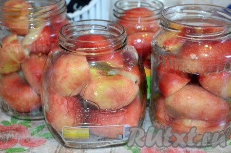 В простерилизованные банки выкладываем половинки персиков.