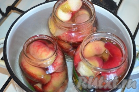 Заливаем горячий сироп в банки с персиками, заполняя баночки до самого верха. У меня получилось 2 банки по 700 миллилитров и 2 банки по 500 миллилитров. Дно достаточно большой кастрюли застилаем полотенцем (или тканевой салфеткой, сложенной в 2-3 раза). Затем в эту кастрюлю ставим банки с персиками в сиропе, прикрываем банки крышками и вливаем в кастрюлю горячую воду. Вода должна закрывать банки по плечики. Ставим кастрюлю с банками на средний огонь, после закипания воды в кастрюле уменьшаем огонь и стерилизуем банки объёмом 700 миллилитров и 1-литровые банки - 15 минут; 500-миллилитровые банки - 10 минут. 