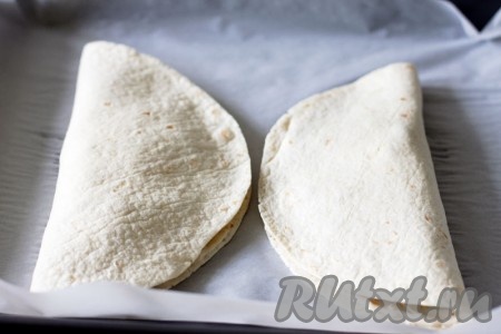 Прикройте начинку свободной стороной лепешек и уберите в духовку до зарумянивания верха.