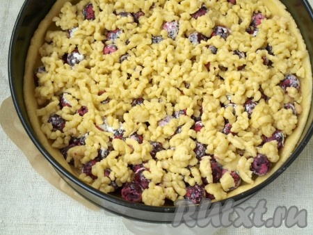 Достать из морозилки отложенное тесто и натереть его на тёрке поверх вишни.