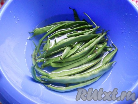 Стручки фасоли поместить в глубокую миску, залить холодной водой.
