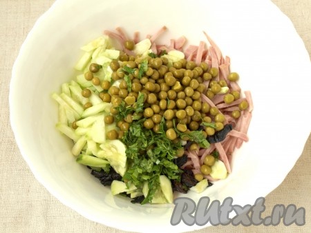 Сложить в большую миску ветчину, огурцы и чернослив, добавить зелёный горошек и нарезанную мелко петрушку.