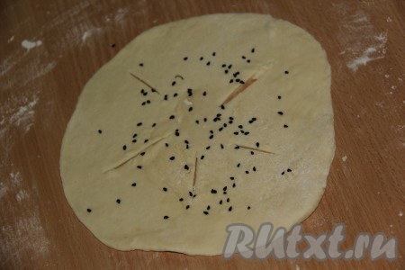 Каждый кусочек теста на присыпанной мукой поверхности раскатать в лепёшку, посыпать кунжутом, ещё раз прокатать скалкой, сделать ножом несколько надрезов.&nbsp;