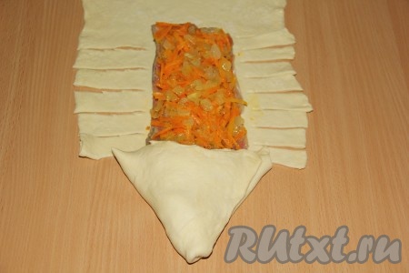 Пирог сформировать в виде рыбы: завернуть хвостовую часть рыбы в виде треугольника (это будет голова). Тесто по бокам нарезать на полоски.