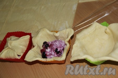 Творожно-ягодную начинку зрительно разделить на такое количество частей, сколько квадратов из теста у вас получились. Эти слойки можно формировать на столе, присыпанной мукой, или в силиконовых формочках, выкладывая квадрат теста так, чтобы края теста свисали с краёв формочек. В центр квадрата из теста, отступая от краёв выложить одну часть начинки из творога и чёрной смородины. Противоположные края квадрата из теста соединить над начинкой, тщательно скрепить, формируя слойку. Если вы формировали слойку на столе, тогда её нужно просто переложить на противень, застеленный пергаментом. Если вы формировали слойки в формочках, тогда просто переставьте формочки со слойками на противень.&nbsp;