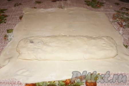 Раскатываем вторую часть теста также тонко. Поверх раскатанного теста ближе к одному из краёв выкладываем рулет с яблочной начинкой (как на фото), подворачиваем боковые края раскатанного теста, слегка накрывая рулет, а затем сворачиваем тесто в рулет так, чтобы внутри нового рулета оказался рулет с начинкой.