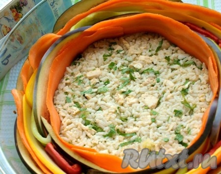 Поверх рисово-куриной массы выкладывать овощи по кругу, чередуя разные полоски. Начинать выкладывать следует от края.