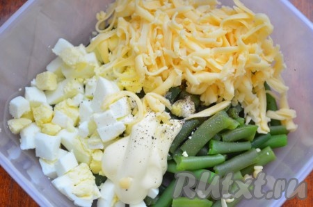 Сложить стручковую фасоль, яйца, сыр, чеснок в миску, посолить, поперчить, заправить салат сметаной (или майонезом), перемешать.