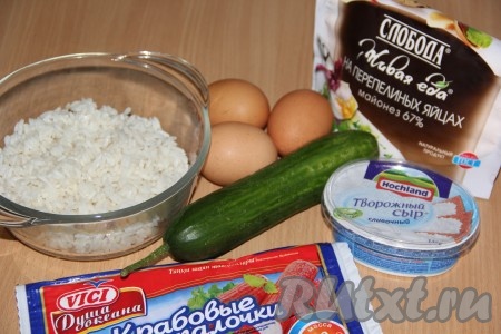 Рис выложить в сито, промыть под проточной водой. Затем переложить рис в кастрюлю с достаточно большим количеством кипящей подсоленной воды, дать снова воде закипеть, перемешать, убавить огонь до минимума, варить рис до готовности (минут 20-25), затем откинуть его на дуршлаг, лишней воде дать стечь, остудить. Сварить яйца вкрутую (в течение 10 минут с момента закипания воды), полностью остудить. Плавленный сыр для этого салата можно взять как творожный, так и сливочный. Если крабовые палочки заморожены, их нужно будет разморозить.