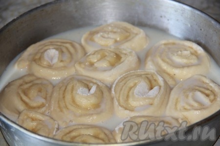 Оставить форму с рулетиками на расстойку в тёплом месте минут на 15-20 (рулетики за это время должны настолько увеличиться в объёме, что заполнят форму). Для приготовления заливки нужно молоко комнатной температуры соединить с сахаром (я люблю не очень сладкую выпечку, поэтому добавила 50 грамм сахара, любители сладкого могут добавить и 100 грамм сахара - главное, ориентируйтесь на свои вкусовые предпочтения), тщательно перемешать. В форму с рулетиками, увеличившимися в объёме, влить половину заливки, поставить в духовку, заранее разогревшуюся до 190 градусов. Выпекать 15 минут.