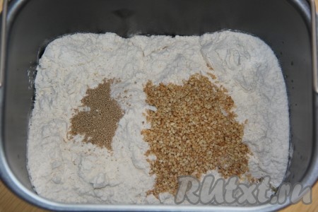 Далее всыпать муку. Соль и сахар всыпать по разным сторонам. Добавить кунжут и дрожжи.
