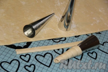 Тесто предварительно разморозить и немного раскатать скалкой. Нарезать тесто на полоски примерно 1,5-2 см шириной. Я для приготовления трубочек использую металлические конусы. Смазать конусы растительным маслом. Накрутить тесто на конусы в виде спирали, слегка растягивая тесто.
