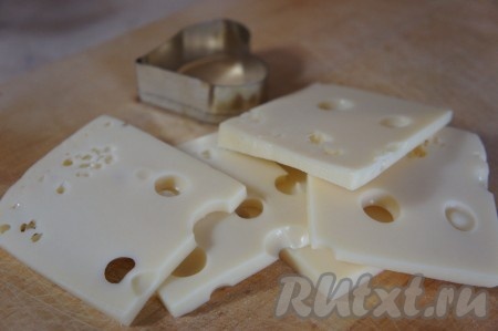 Сыр нарезаем на кусочки и с помощью той же формы, которой вырезали хлеб, вырезаем фигурки из сыра.