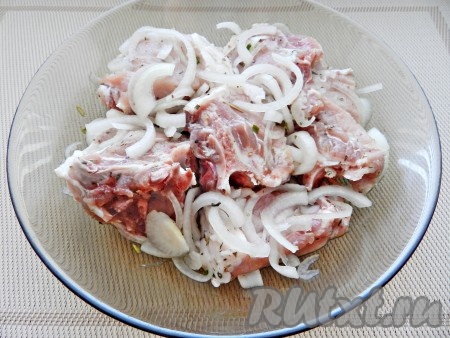 Свиные ребрышки вымыть, обсушить и разрезать. Нарезать полукольцами луковицу. Смешать мясо с луком, солью, перцем и сухими травами. Оставить на 2 часа в холодильнике.
