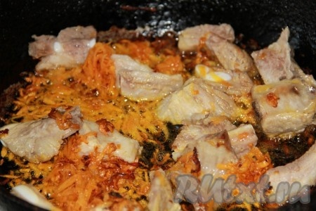Пока варится картофель, обжарим мясо с овощами. Для этого сварившееся мясо нужно отделить от костей и нарезать на небольшие кусочки. Лук и морковь очистить. Нарезать лук достаточно мелко. Морковку натереть на крупной тёрке. В сковороде разогреть растительное масло, выложить морковку с луком и обжаривать овощи на среднем огне, периодически помешивая, 6-7 минут (до мягкости овощей), затем добавить кусочки свинины, отделённые от костей, перемешать и обжарить до подрумянивания мяса со всех сторон.