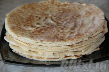 Готовый корж снимаем со сковороды и сразу обрезаем, придавая ему круглую форму. Очень удобно обрезать коржи, прикладывая к ним сверху перевёрнутую тарелку нужного диаметра. Оставшиеся обрезки в дальнейшем будем использовать для посыпки торта. Постепенно один за другим жарим все коржи, обрезаем их и даём полностью остыть.