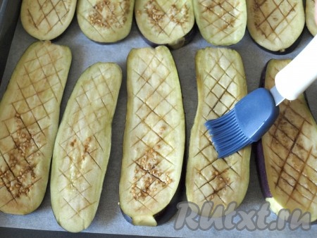 По истечении 30 минут баклажаны промокнуть салфеткой, выложить в один слой на противень, застеленный пергаментом. Смазать баклажаны при помощи кисточки подсолнечным маслом.