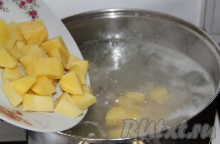 В закипевший бульон выкладываем очищенный картофель, нарезанный на кубики.