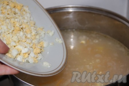 После того как рис с картошкой станут достаточно мягкими, добавляем в суп мелко нарезанные варёные яйца.