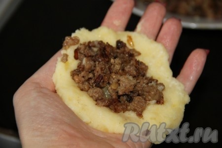 Смачиваем руки в воде и приступаем к формированию картопляников с мясным фаршем внутри, для этого берём небольшую часть пюре, разминаем на ладони в небольшую лепёшку. В центр лепёшки выкладываем часть мясного фарша (как на фото) и защипываем края, формируя котлету. Не забывая смачивать руки водой, формируем все картофельные котлетки.