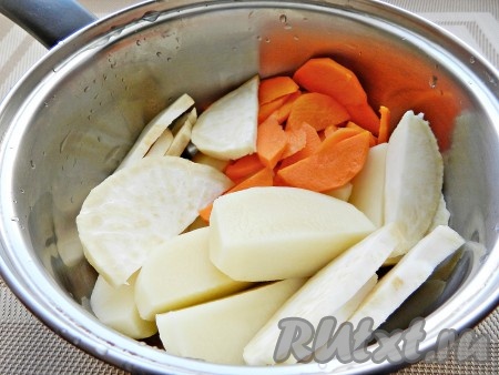 Морковку, корень сельдерея и картошку нарезать на небольшие кусочки, сложить в небольшую кастрюлю, влить 500 миллилитров холодной воды и поставить на огонь. Когда вода закипит, добавить соль, уменьшить огонь и варить овощи до готовности (примерно 20 минут).