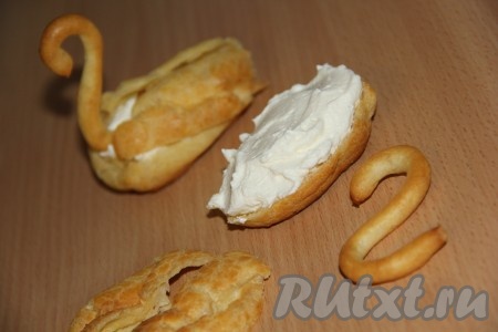 Сливки взбить с сахарной пудрой до стойких пиков. Сформировать лебедей: взять 1 тело лебедя, срезать верхушку острым ножом на 1/3 или на половину. Верхнюю часть разрезать пополам, это будут крылья. В нижнюю часть выложить сливки, затем закрыть крыльями и вставить голову.
 