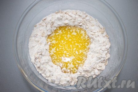 Затем в серединке смеси сделать углубление и влить теплое растопленное масло, перемешать до липкой крошки.