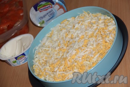 Яйца натереть на крупной тёрке или мелко нарезать. Выложить яйца на авокадо и разровнять. Слегка смазать майонезом.