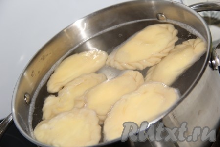 В кастрюлю налить воду, добавить щепотку соли и поставить на огонь. В кипящую воду аккуратно по одному опустить вареники. Варить вареники 10-15 минут, затем достать шумовкой.
