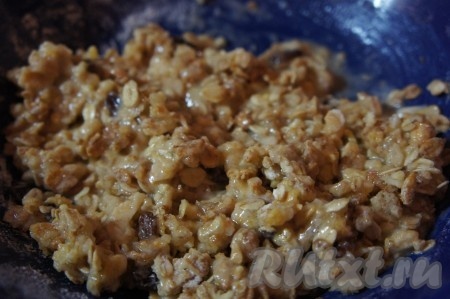 В полученную смесь влить воду, смесь растительного масла и тёплого растопленного сливочного масла, перемешать и разложить получившуюся смесь тонким слоем поверх яблок.
