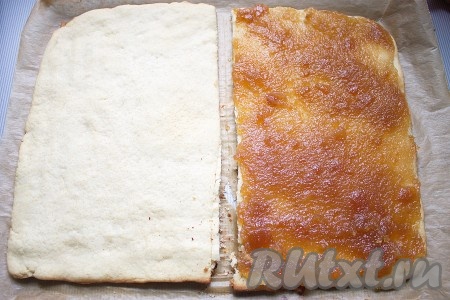 Тем временем слегка нагреть яблочное повидло, чтобы его было легче намазывать на корж. Готовые песочные коржи достать, переложить на стол вместе с пергаментом. Поверхность одного равномерно смазать повидлом и оставить остывать. Затем корж с повидлом накрыть вторым коржом и слегка прижать.
