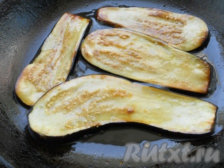 По прошествии 30 минут пластины баклажанов промыть водой, обсушить бумажным полотенцем. В сковороде разогреть растительное масло, уменьшить огонь до среднего, выложить несколько пластин баклажанов. Обжарить баклажаны с двух сторон до чуть золотистой корочки.