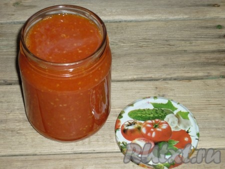 Проваренную аджику из помидоров и яблок разложить в подготовленные стерилизованные банки&nbsp;и закатать.
