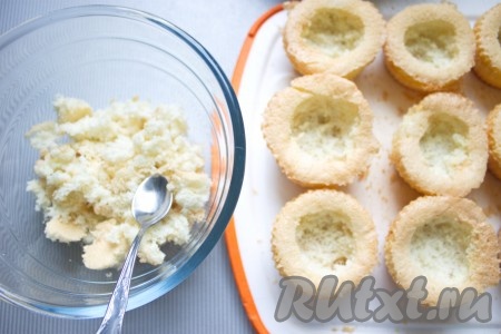 У каждого кексика чайной ложечкой аккуратно вырезать серединку. Мякиш бисквита чуть перетереть руками и оставить для украшения.