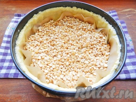 Чтобы тесто не вздулось при выпечке, рекомендуется выкладывать на него груз. В качестве груза можно использовать сухие горох или фасоль. На тесто положить круг из бумаги, высыпать сверху горох (или фасоль) и поставить форму в разогретую до 200 градусов духовку на 20-25 минут (корж должен стать красивого светло-золотистого цвета). Готовый корж достать из духовки, дать немного остыть, убрать бумагу с горохом (или фасолью). Кстати, этот горох (или фасоль) можно будет использовать для приготовления супов и других блюд.