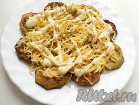 Следующим слоем разложить половину натёртого сыра и нанести сеточку из майонеза, поперчить.