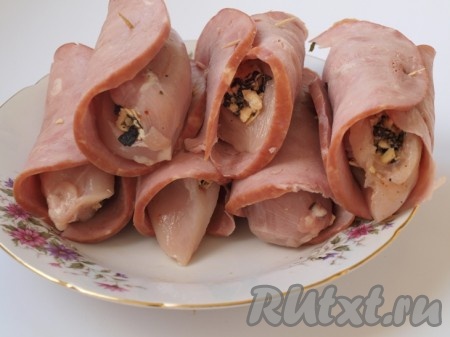 Ветчину тонко нарезаем. Куриное филе заворачиваем в ломтики ветчины. Для того чтобы рулетики при жарке не развалились, их можно для надёжности обвязать нитью или сколоть зубочистками. Убираем куриные рулетики в ветчине в морозилку минут на 30. За это время можно приготовить соус. Мелко нарезаем помидоры, очищенные от кожуры. Лук нарезаем тонкими полукольцами. Лук слегка обжариваем на растительном масле, затем добавляем помидоры, соль, перец и тушим минут 10-15 до мягкости помидоров.
