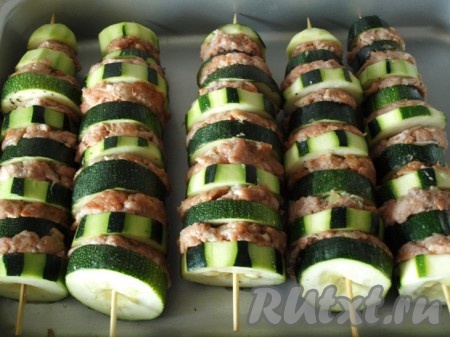 Мясной фарш смешиваем с яйцом, порезанным луком, чесноком, пропущенным через пресс, солью, перцем, томатной пастой. Фарш нужно тщательно вымесить, он должен быть сухим. Нанизываем на шпажку кабачок, затем фарш, плотно придавливая к шпажке, затем опять кабачок и т.д.  По краям нашего шашлыка должны быть кабачки.
