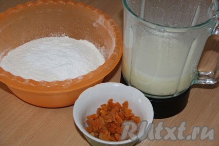 Обдаём курагу кипятком, а затем промываем, обсушиваем и режем на кусочки. Взбиваем яйца с сахаром миксером до увеличения в объёме и побеления массы (в течение минут 5). Затем в яичную смесь вливаем кефир, растительное масло и ещё раз хорошо взбиваем.