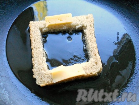 В сковороду влить растительное масло, нагреть. Огонь сделать минимальным. Поместить в сковороду один подготовленный ломоть хлеба. На края, с двух сторон, поместить по тонкому кусочку сыра.
