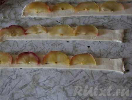 На полоски из теста выложить яблоки, оставляя один край чистым (как на фото).