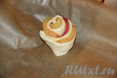 Полоски из слоёного теста скрутить в рулетики с яблоками (розочки), начиная с края, на котором есть яблоки, плотно скрепить получившийся рулет чистым концом теста (без яблок).