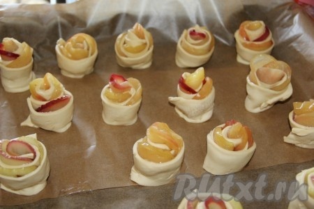 Аналогично сформировать все розочки с яблоками из слоёного дрожжевого теста. Получившиеся розочки поставить на противень, застеленный бумагой для выпечки.