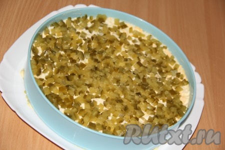 Маринованные огурцы нарезаем мелкими кубиками и ровно выкладываем следующим слоем.
