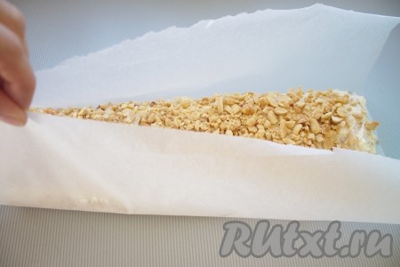 Насыпать орешки на пергамент, взять пергамент за края и покатать рулет, чтобы орешки хорошенько прилипли к поверхности. 